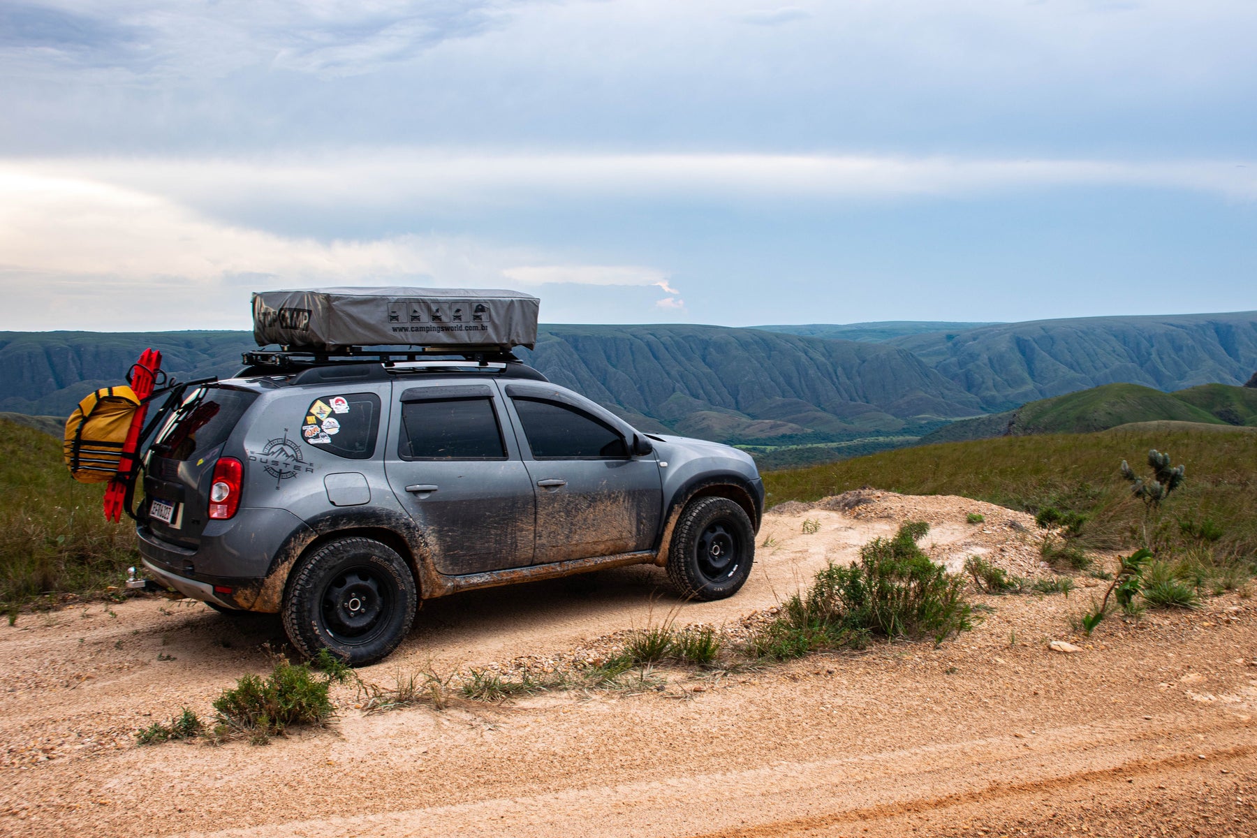 An off-road vehicle on a dirt track overlooking mountain scenery